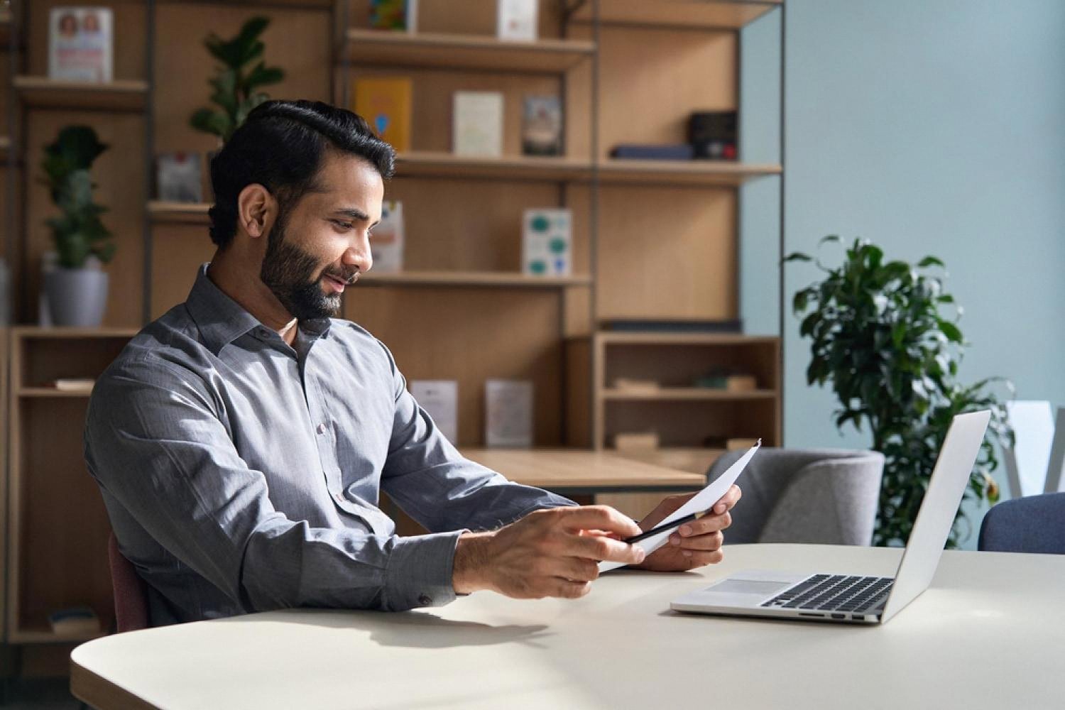 Professional man reviewing documents at a laptop in a UAE office setting